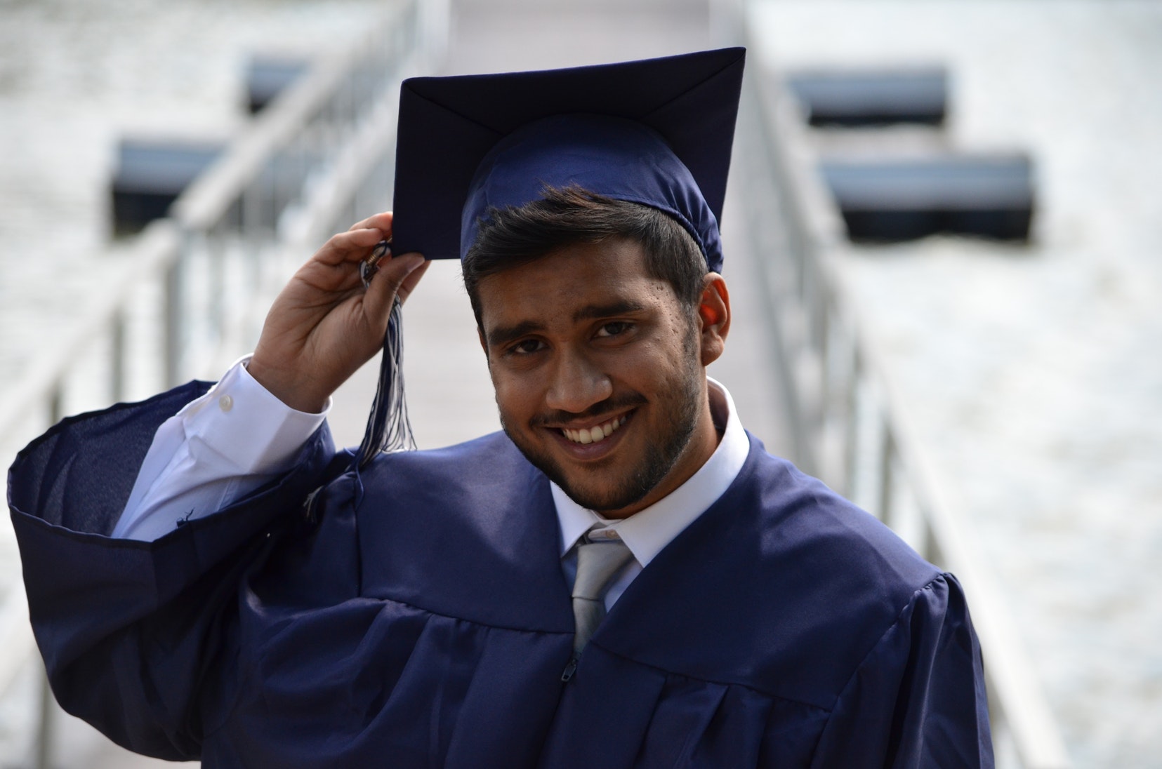 A picture of a graduate holding their hat and smiling.