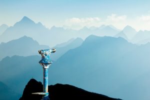 Public binoculars and Mountain Silhouettes at Sunrise. Foresight and vision for new business concepts and creative ideas. Alps, Allgau, Bavaria, Germany.